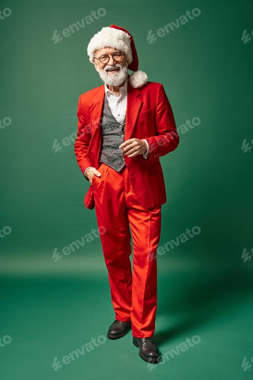 Preview: cheerful man dressed as Santa with christmassy hat posing with one hand in pocket, winter concept