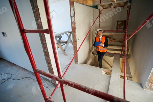 Preview: Construction foreman writing on clipboard while climbing stairs