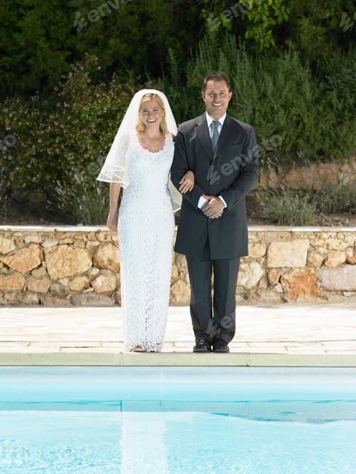 Preview: Bride and groom by edge of swimming pool