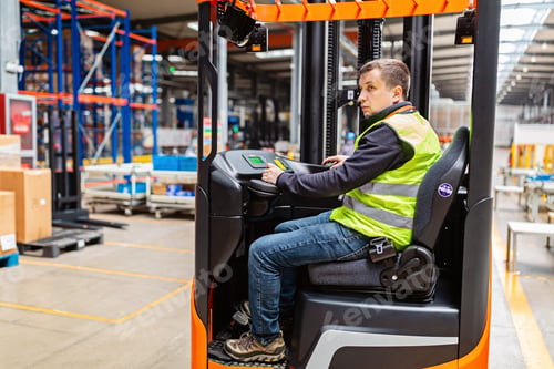 Preview: Young Caucasian man employee is working on modern factory. Forklift operator is doing job