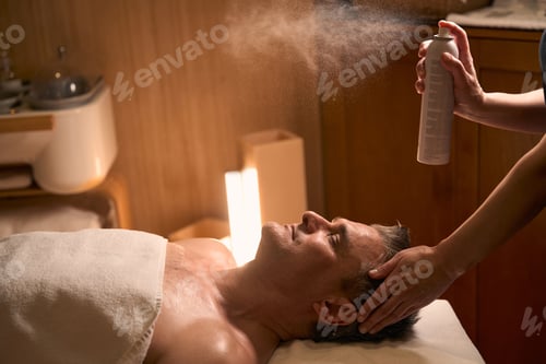 Preview: Experienced spa salon beautician hydrating client skin