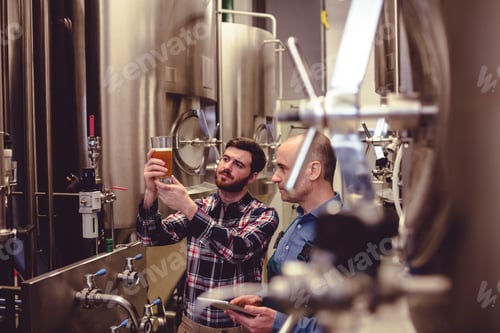 Preview: Owner and worker examining beer in glass