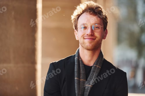 Preview: Portrait of elegant young man in glasses and formal classy clothes outdoors in the city