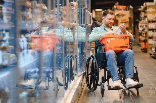 Preview: Customer in wheelchair choosing products in supermarket refrigerator section