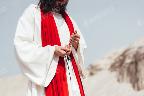 Preview: cropped image Jesus holding wooden rosary and praying in desert