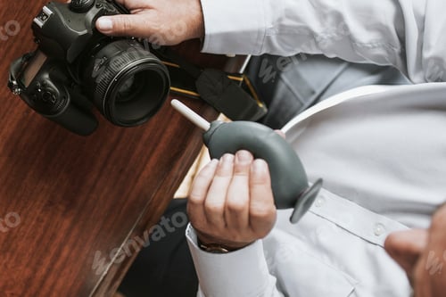 Preview: Man cleaning his camera lens with a rubber air blower