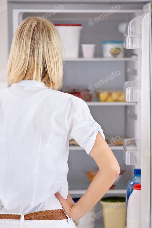 Preview: What to eat. Rearview of a young woman looking in her fridge.