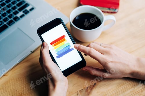 Preview: Female hands hold a mobile phone in the workplace with a laptop
