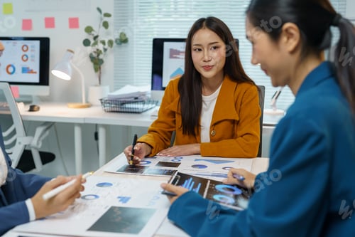 Preview: Asian businesswomen analyzing financial data and discussing company strategy using charts, graphs, a