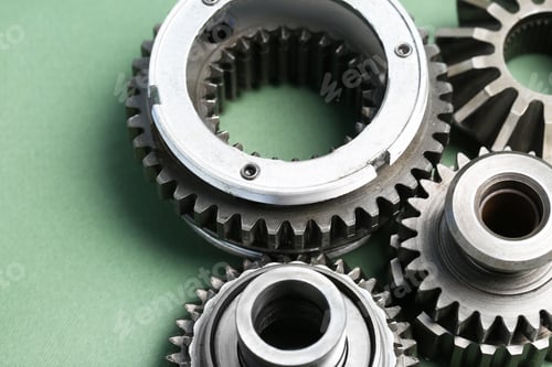 Preview: Different stainless steel gears on light green background, closeup