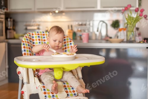 Preview: One year old girl having balanced meal in baby eating chair, healthy balanced nutrition for child,