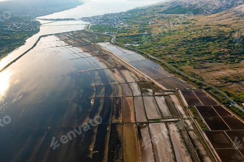 Preview: Aerial view of salt pans at sunset showcasing seawater evaporation and salt production.