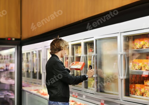 Preview: Teenager Choosing Frozen Food From A Supermarket Freezer