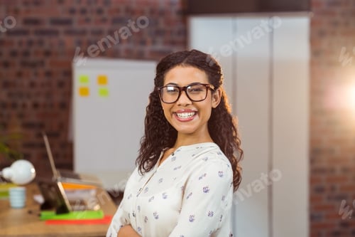 Preview: African American woman standing at desk in workspace using laptop and holding mug near whiteboard