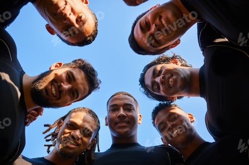 Preview: Low angle portrait of a diverse group of sportsmen huddled together before playing a game of rugby