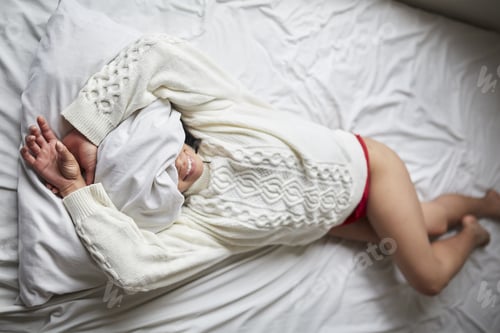 Preview: Young Latin woman laying on the bed happily smiling with her face covered