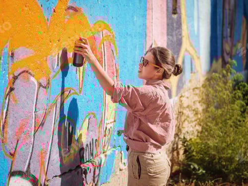 Visualização: Linda jovem fazendo um grafite colorido com spray de aerossol na parede da rua urbana.