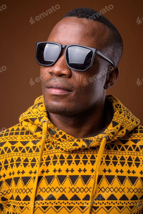 Preview: Studio shot of young African man against brown background