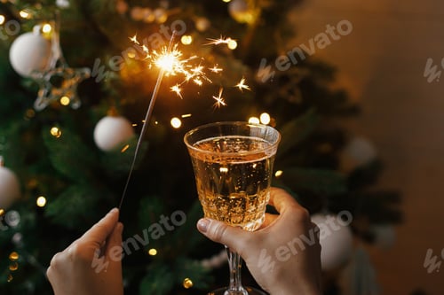 Visualização: Mulher comemorando com fogos de artifício e taça de champanhe contra as luzes da árvore de natal. Feliz Ano Novo