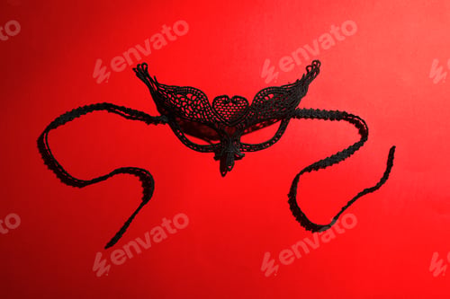 Preview: Black lace mask on red background, top view. Accessory for sexual role play