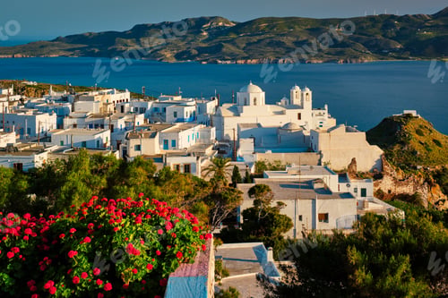 Preview: Picturesque scenic view of Greek town Plaka on Milos island over red geranium flowers