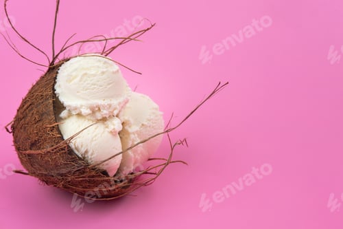 Preview: Vanilla ice cream balls in an empty coconut decorated with mint leaves on a pink background