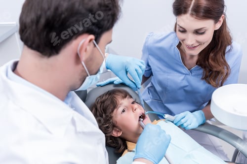 Preview: dentists treating teeth of little patient in dentist chair in hospital