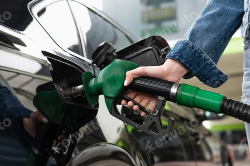 Preview: cropped view of woman fueling car on gas station