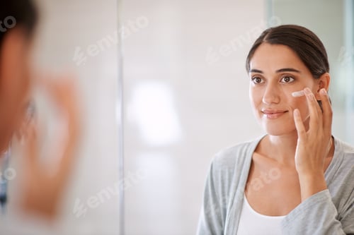 Preview: Keeping her skin soft and smooth. Shot of a beautiful woman applying moisturizer to her face.