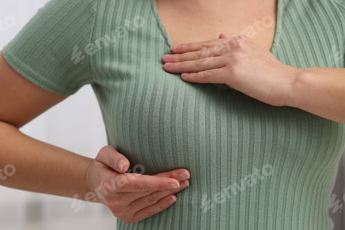 Preview: Mammology. Woman doing breast self-examination indoors, closeup