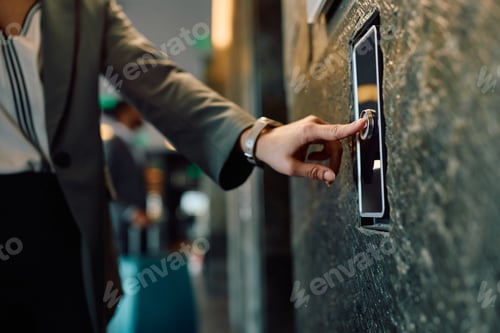 Preview: Close up of businesswoman pressing elevator button in hotel lobby.