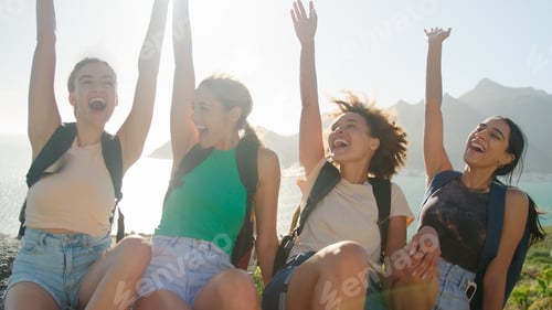 Preview: Female Friends With Backpacks And Hands In Air On Vacation Taking Break On Hike Through Countryside