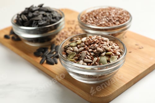 Preview: Different seeds in bowls on white table, closeup