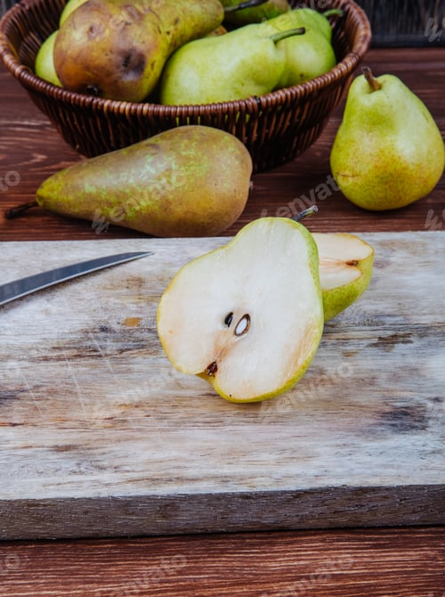 Preview: side view of fresh ripe pears and halves on a wooden cutting board with kitchen knife