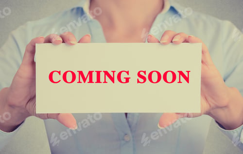 Preview: Businesswoman Hands Holding White Card Sign With Coming Soon Text Message Isolated On Grey Wall