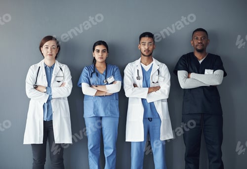 Preview: Shot of a group of doctors standing against a grey background at work