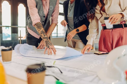 Preview: Multiracial team of architects having a meeting while using blueprints