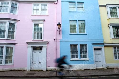 Preview: Horizontal shot of a building in pink, blue and yellow colors and a man riding bicycle
