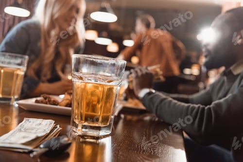 Preview: multiethnic man and woman eating and drinking at bar
