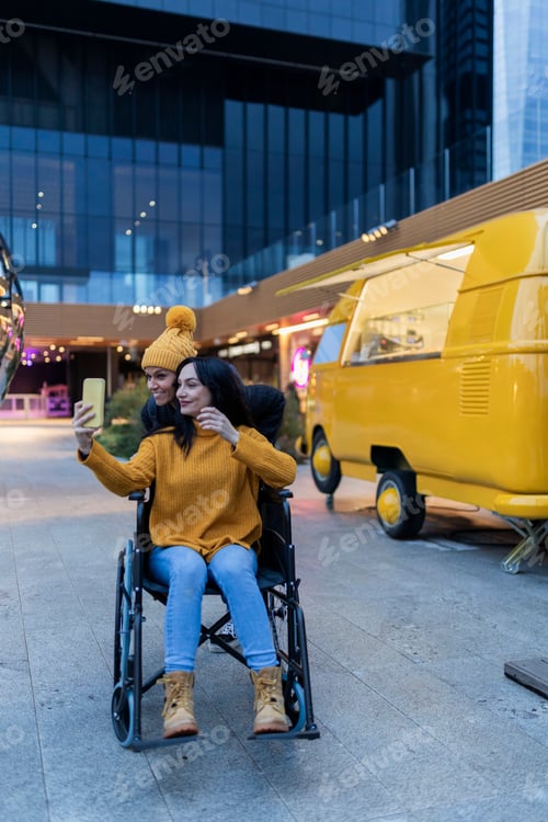 Preview: fun friends spending time together while one of them is pushed in her wheelchair and taking a selfie