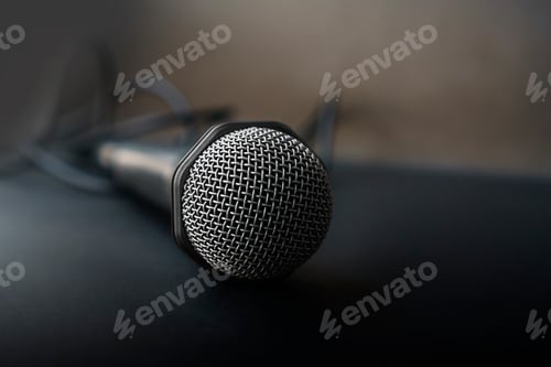 Preview: Microphone for karaoke with a wire isolated on black. top view, flat lay, copy space for your text