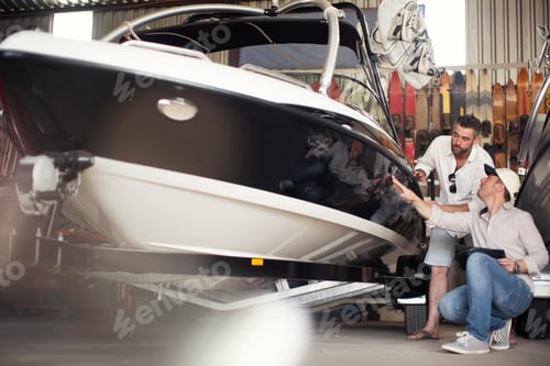 Preview: Two men inspecting a boat in a workshop.