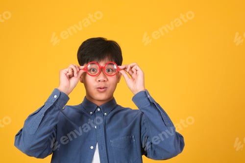 Preview: Portrait of asian nerd man with red glasses on yellow background.