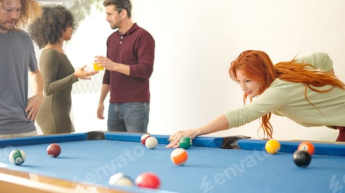 Preview: Woman hitting a ball playing pool with friends at home