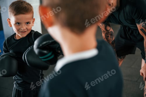 Preview: Having fun by practicing. Young tattooed coach teaching the kids boxing techniques