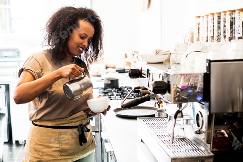 Preview: Woman barista preparing a cup of coffee in a coffee shop.