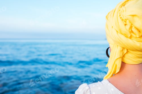 Preview: Female with a yellow scarf enjoying the sea view - concept: fight against cancer
