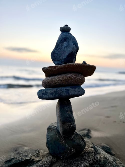 Preview: Stone pyramid of rounded stones by the sea at sunset