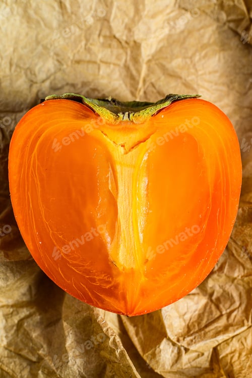 Preview: Half a persimmon on a wooden tray. Close up. Top view. Space for text