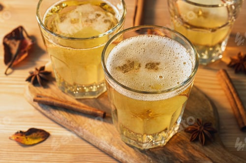 Preview: Golden spiced apple cider with cinnamon and star anise in faceted glasses on rustic board